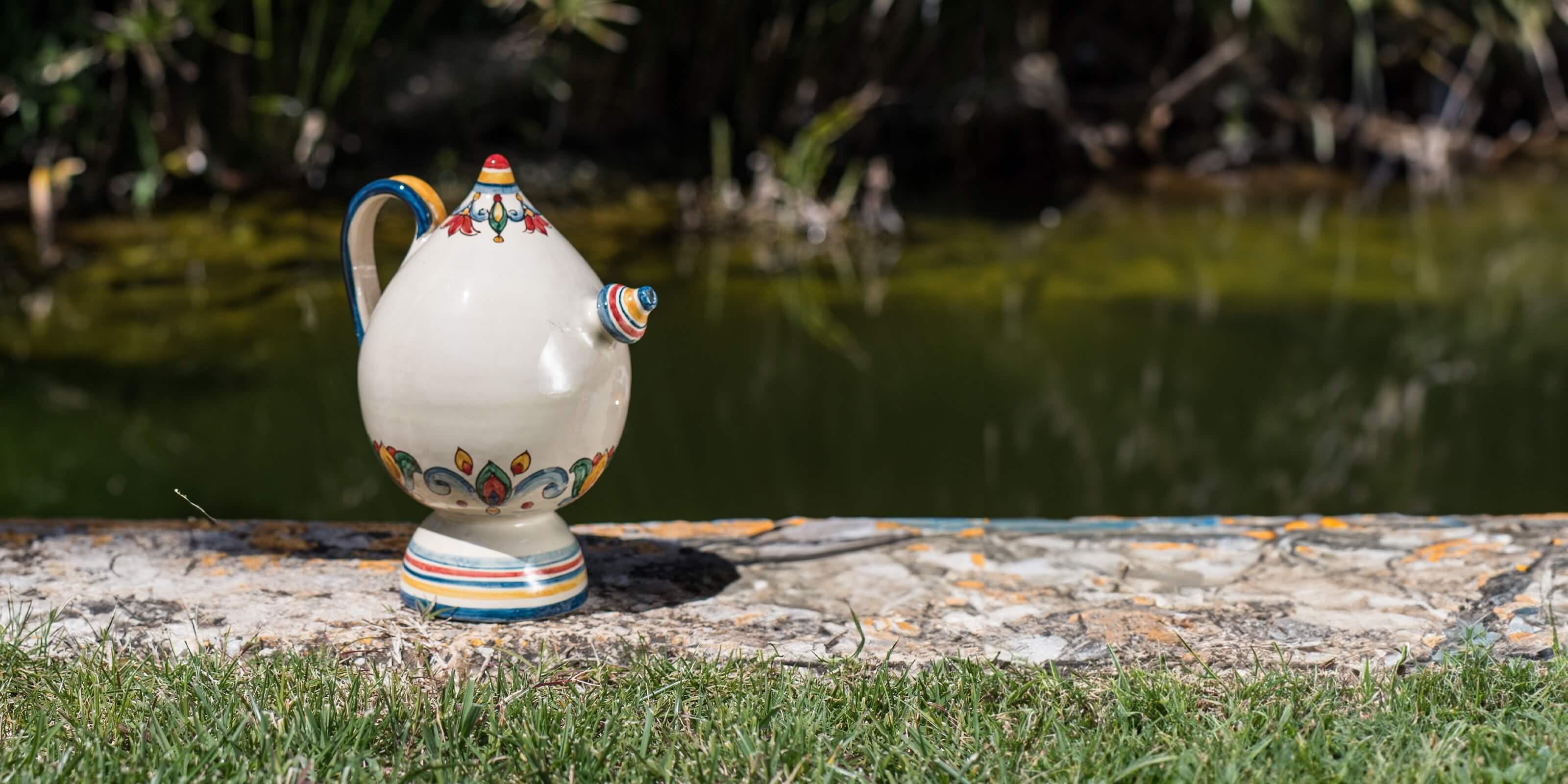 Ceramica di Caltagirone fatta a mano, brocca decorata e colorata su pietra vicino a laghetto