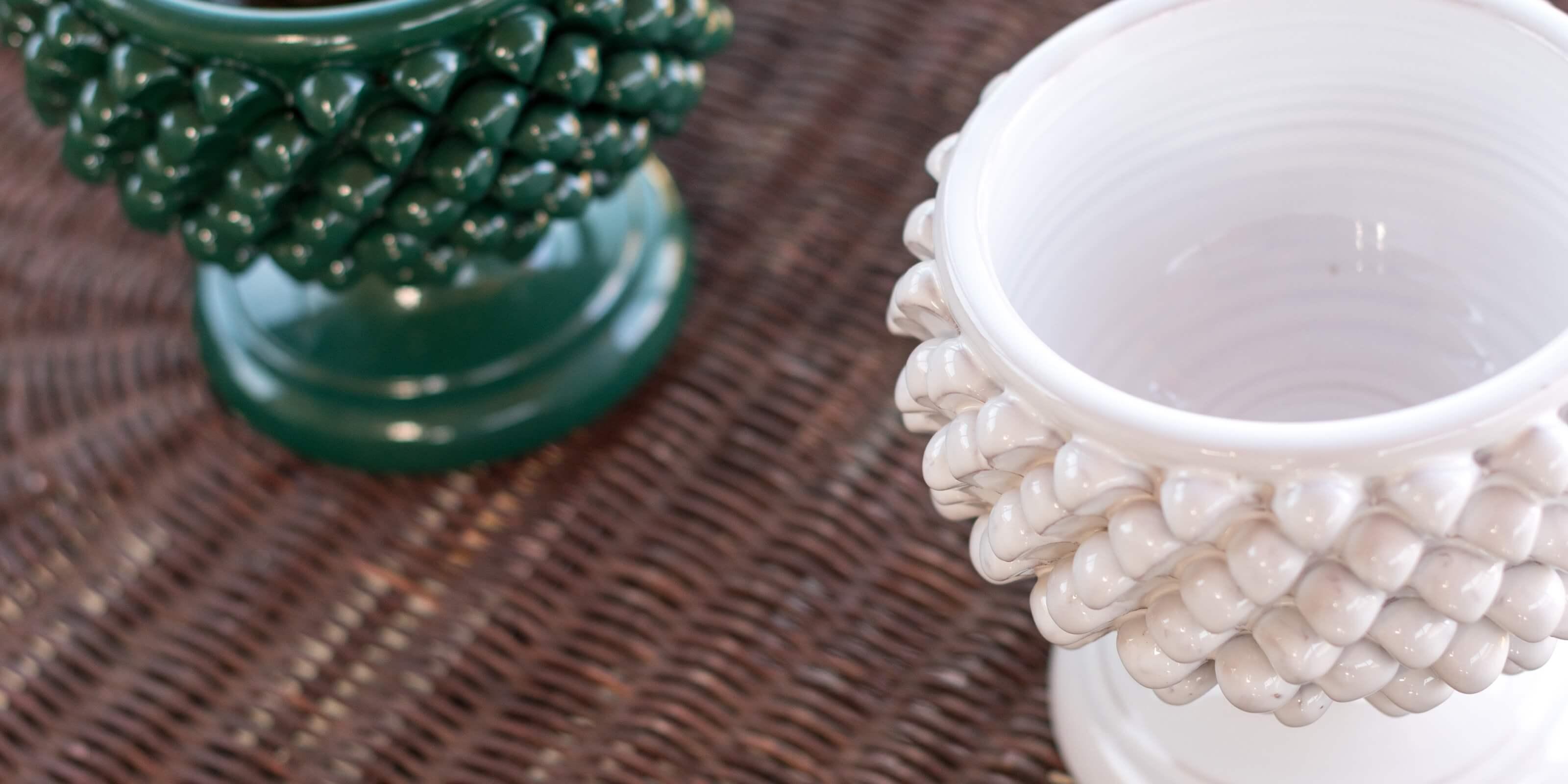 Vasi artigianali ceramiche Caltagirone Sofia fatti a mano, uno bianco e uno verde, su sfondo intrecciato