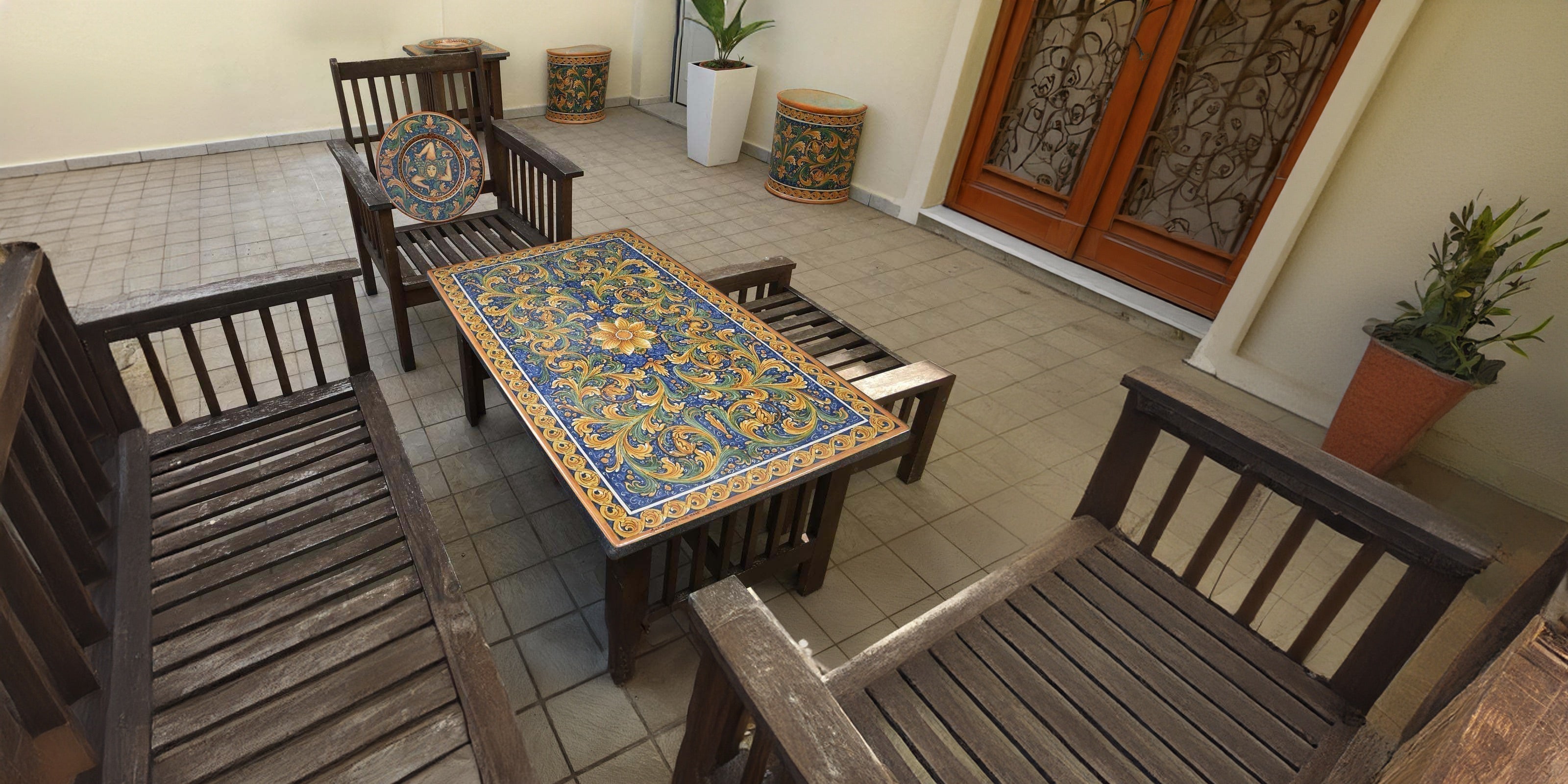 Tavolo con ceramiche Caltagirone fatti a mano e sedie in legno su patio piastrellato