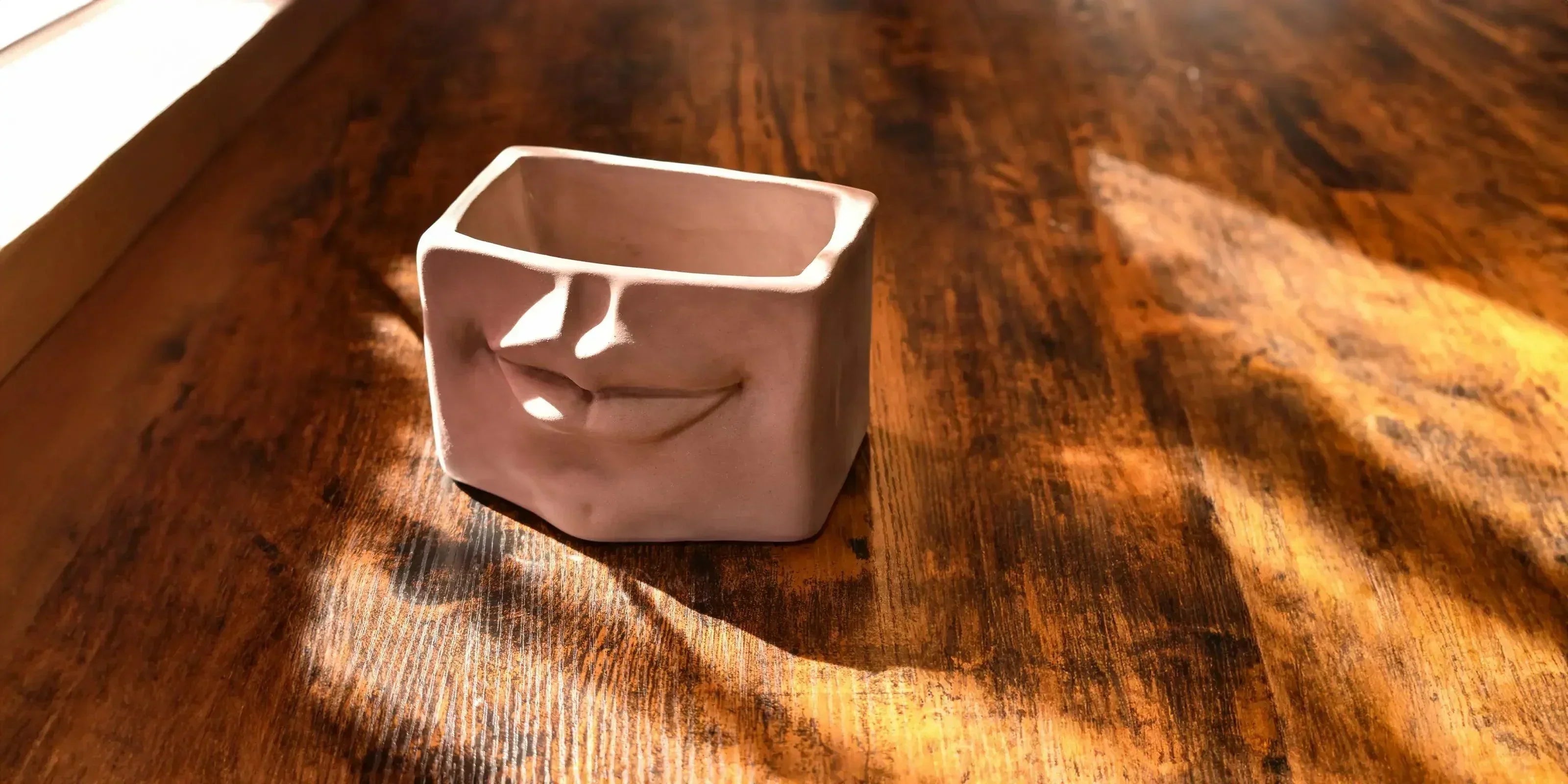 Vaso in ceramica tortora opaco con volto stilizzato su tavolo in legno, ceramiche caltagirone fatti a mano