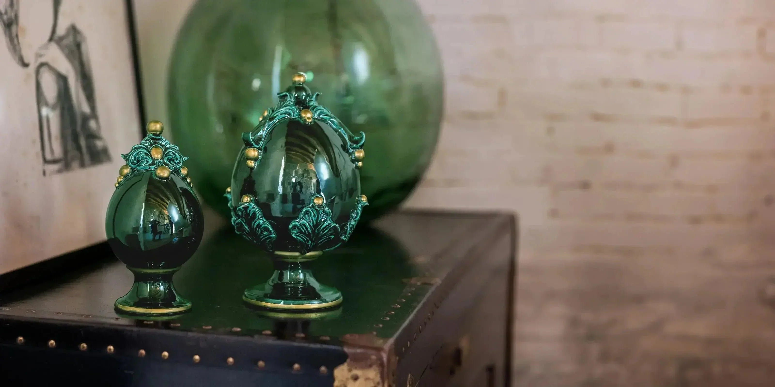 Uova ornamentali verdi con dettagli dorati sulle ceramiche di Caltagirone fatte a mano su mobile scuro
