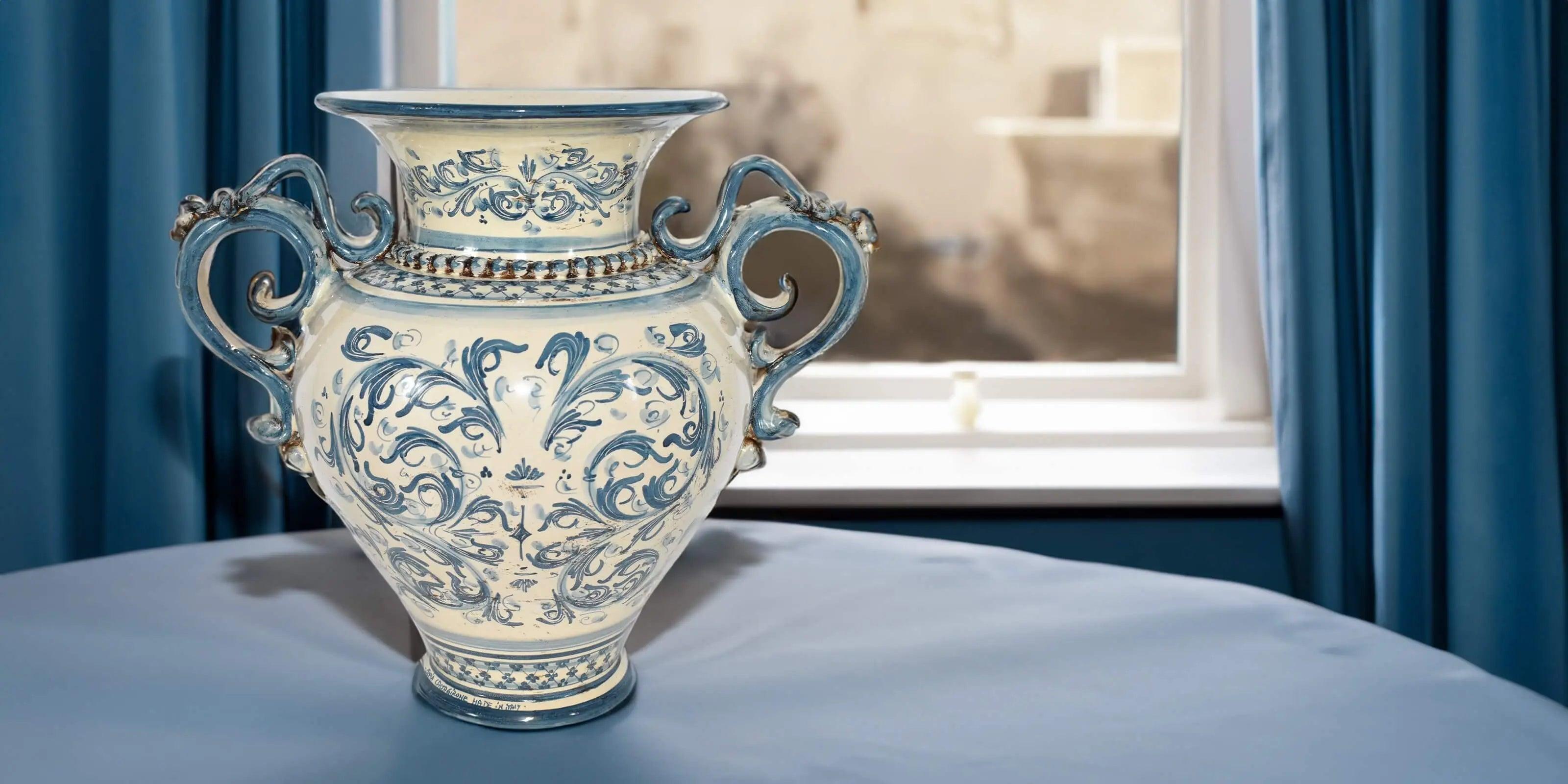 Vaso decorativo in ceramica di Caltagirone fatta a mano con dettagli blu su tavolo davanti a finestra