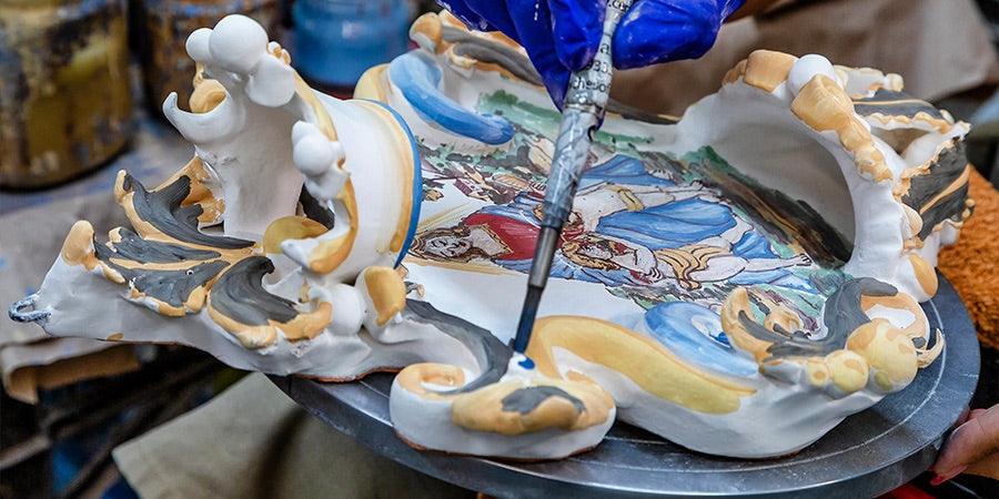 Ceramiche Caltagirone fatti a mano, mano con guanto blu dipinge decorazioni tradizionali su ceramica artigianale
