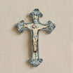 Mono Blue Caltagirone ceramic crucifix hanging on a light wall, handmade with Christ in relief and hand-painted blue scrolls